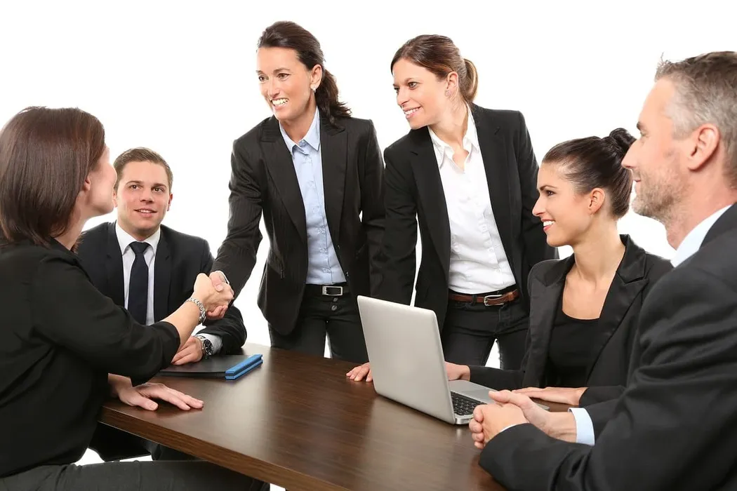 Dubai Business Setup - Group of professionals in business attire around a table, shaking hands.